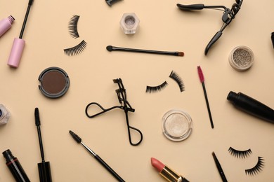 Photo of Flat lay composition with eyelash curlers, makeup products and accessories on beige background
