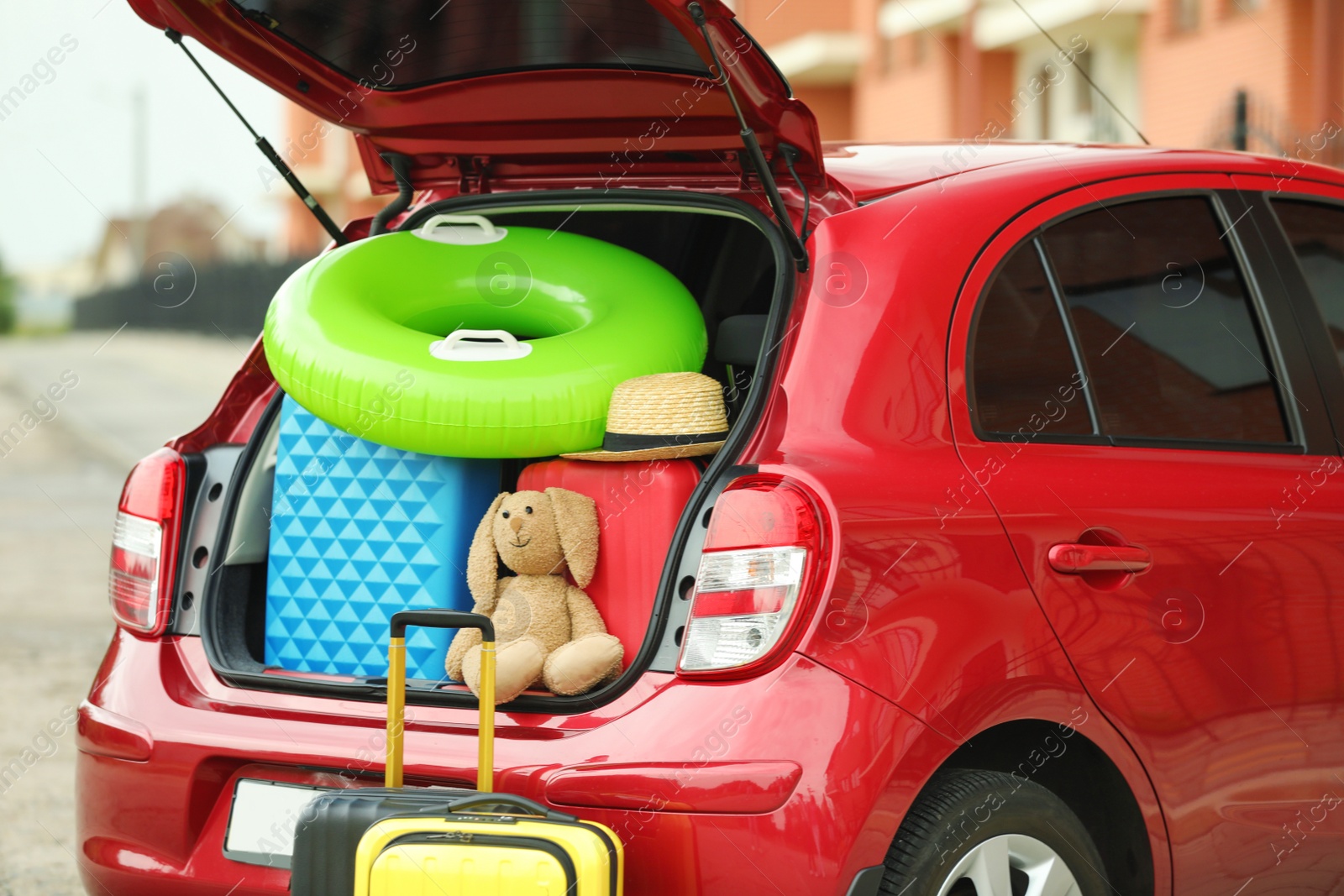 Photo of Suitcases, toys and hat in car trunk, closeup