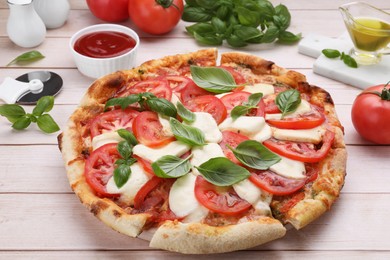 Photo of Delicious Caprese pizza with tomatoes, mozzarella and basil served on light wooden table