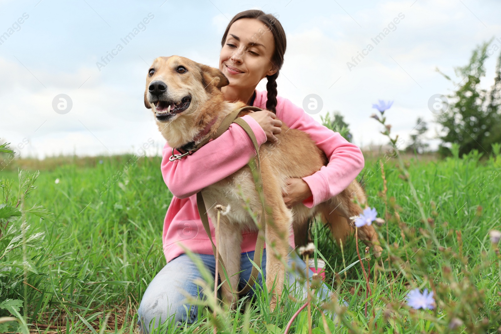 Photo of Female volunteer with homeless dog at animal shelter outdoors