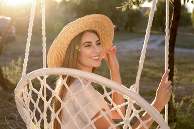 Photo of Young woman resting in hammock chair outdoors on sunny day. Summer vacation