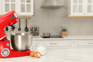 Photo of Modern red stand mixer, eggs and container with flour on white marble table in kitchen, space for text