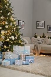 Photo of Many gift boxes under decorated Christmas tree in room