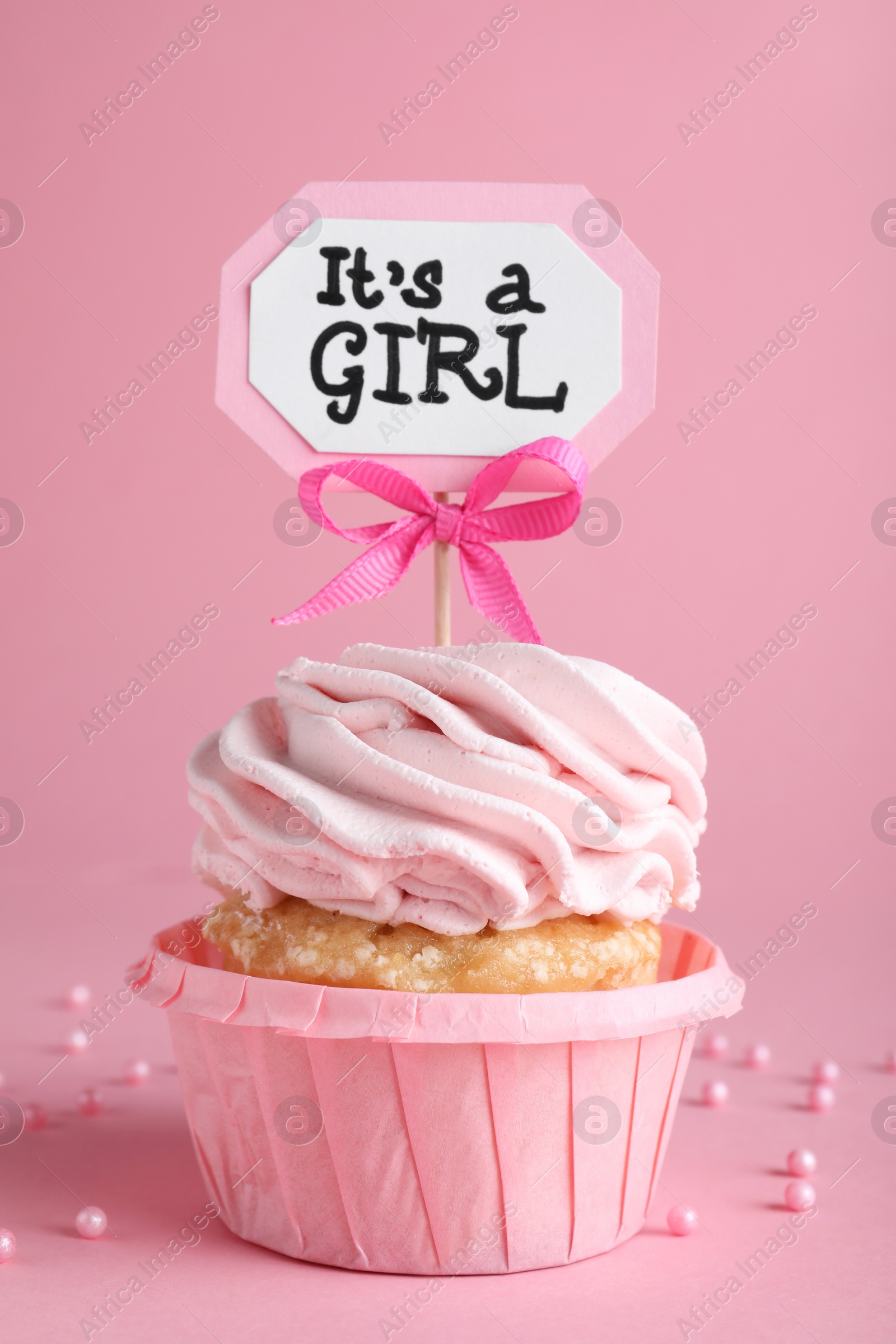 Photo of Beautifully decorated baby shower cupcake for girl with cream and topper on pink background