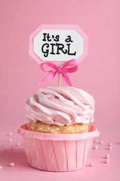 Beautifully decorated baby shower cupcake for girl with cream and topper on pink background