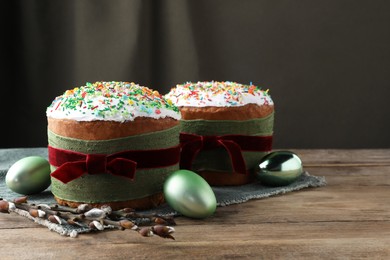 Photo of Traditional Easter cakes, painted eggs and willows on wooden table. Space for text