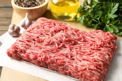 Photo of Raw ground meat, parsley and garlic on table, closeup