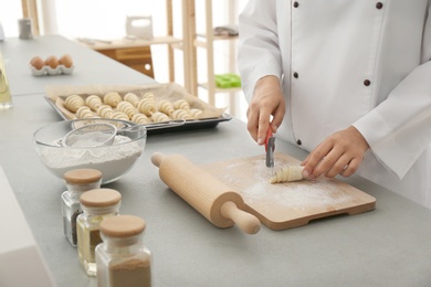Photo of Female pastry chef preparing croissant at table in kitchen, closeup
