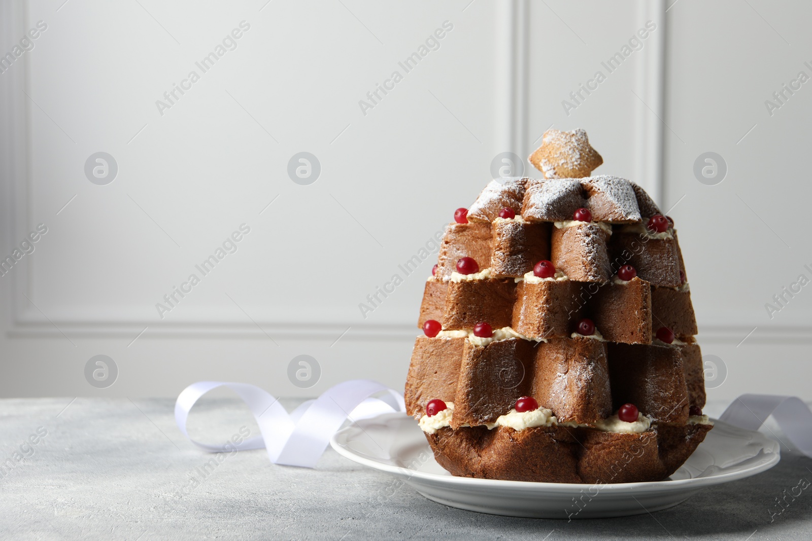 Photo of Delicious Pandoro Christmas tree cake with powdered sugar and berries on white table. Space for text