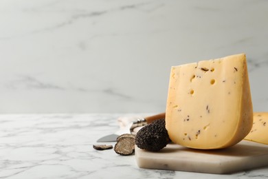 Photo of Delicious cheese and fresh black truffles on white marble table. Space for text