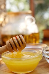 Photo of Delicious honey and dipper on wooden tray, closeup