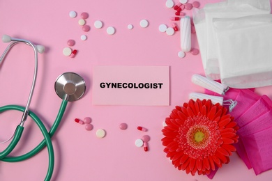 Flat lay composition with stethoscope, period supplies and pills on color background. Gynecological checkup