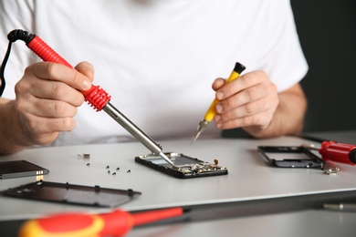 Photo of Technician repairing mobile phone at table, closeup