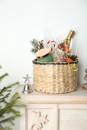 Photo of Wicker basket with gift set and Christmas decor on shelf