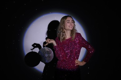 Photo of Beautiful woman with disco ball in spotlight on dark background