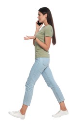 Young woman talking on phone while walking against white background