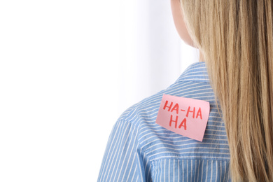 Woman with HA-HA-HA sticker on back against light background, closeup. April Fool's Day