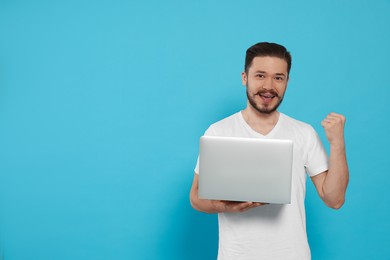 Photo of Happy man with laptop on light blue background. Space for text