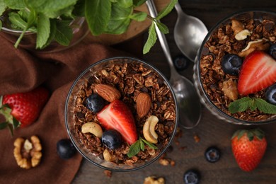 Photo of Tasty granola, berries, nuts and mint on wooden table, flat lay