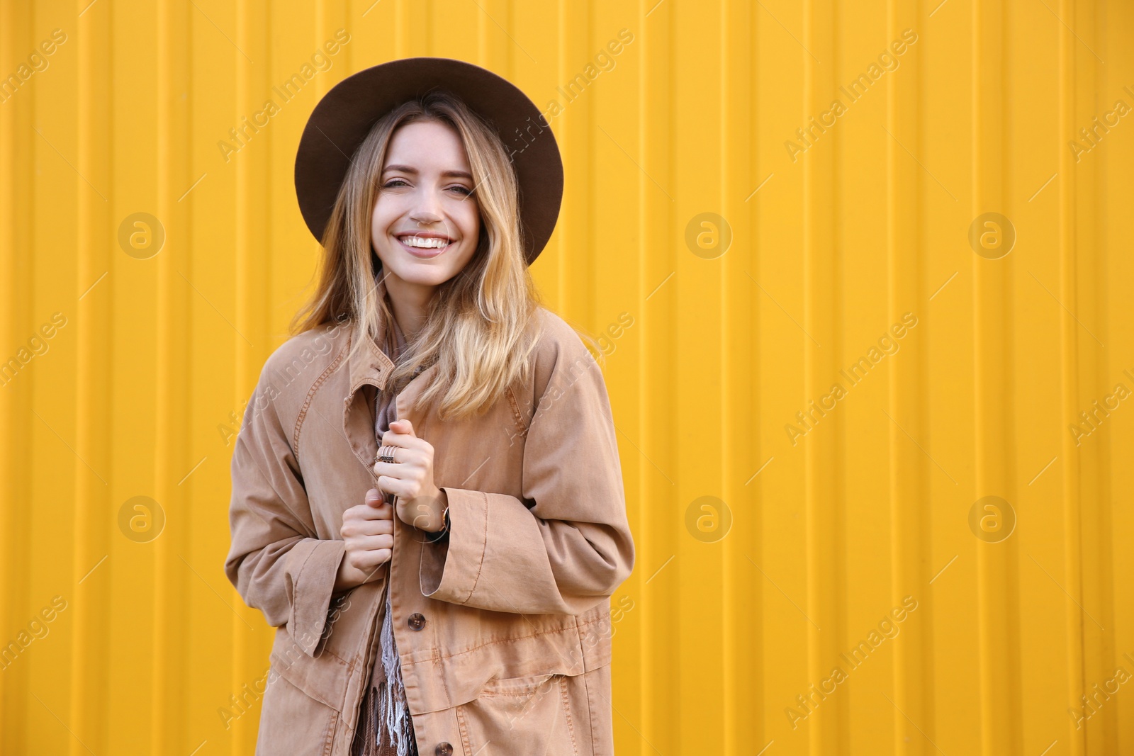 Photo of Beautiful young woman in stylish autumn clothes near yellow fence. Space for text