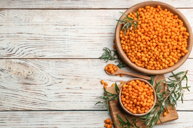 Fresh ripe sea buckthorn on white wooden table, flat lay. Space for text