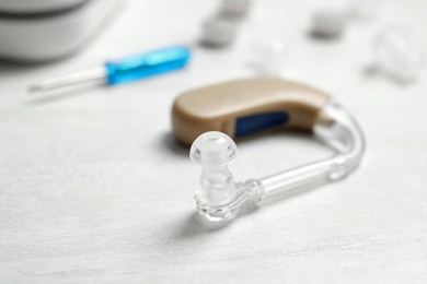 Photo of Hearing aid on white table, closeup. Medical device
