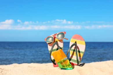 Composition with beach accessories on sand near sea in summer. Space for text