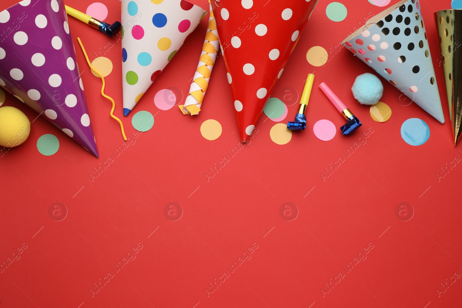 Photo of Flat lay composition with party hats and other festive items on red background. Space for text