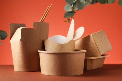 Photo of Eco friendly food packaging. Paper containers, tableware and eucalyptus branch on color background