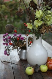 Photo of Beautiful autumn composition with different flowers on wooden table outdoors