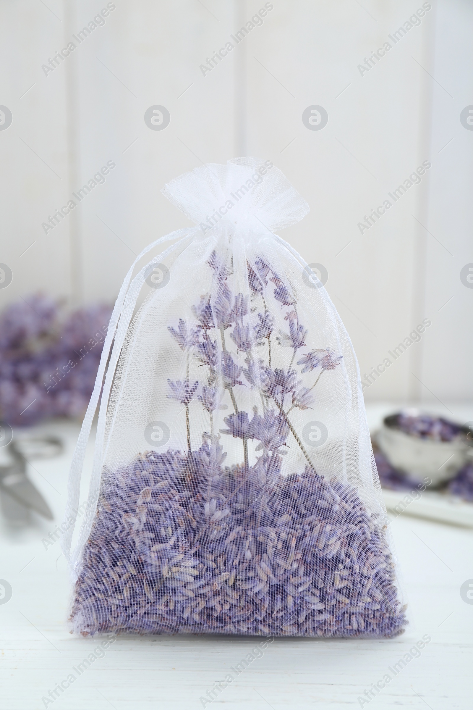 Photo of Scented sachet with dried lavender flowers on white table