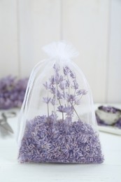 Photo of Scented sachet with dried lavender flowers on white table