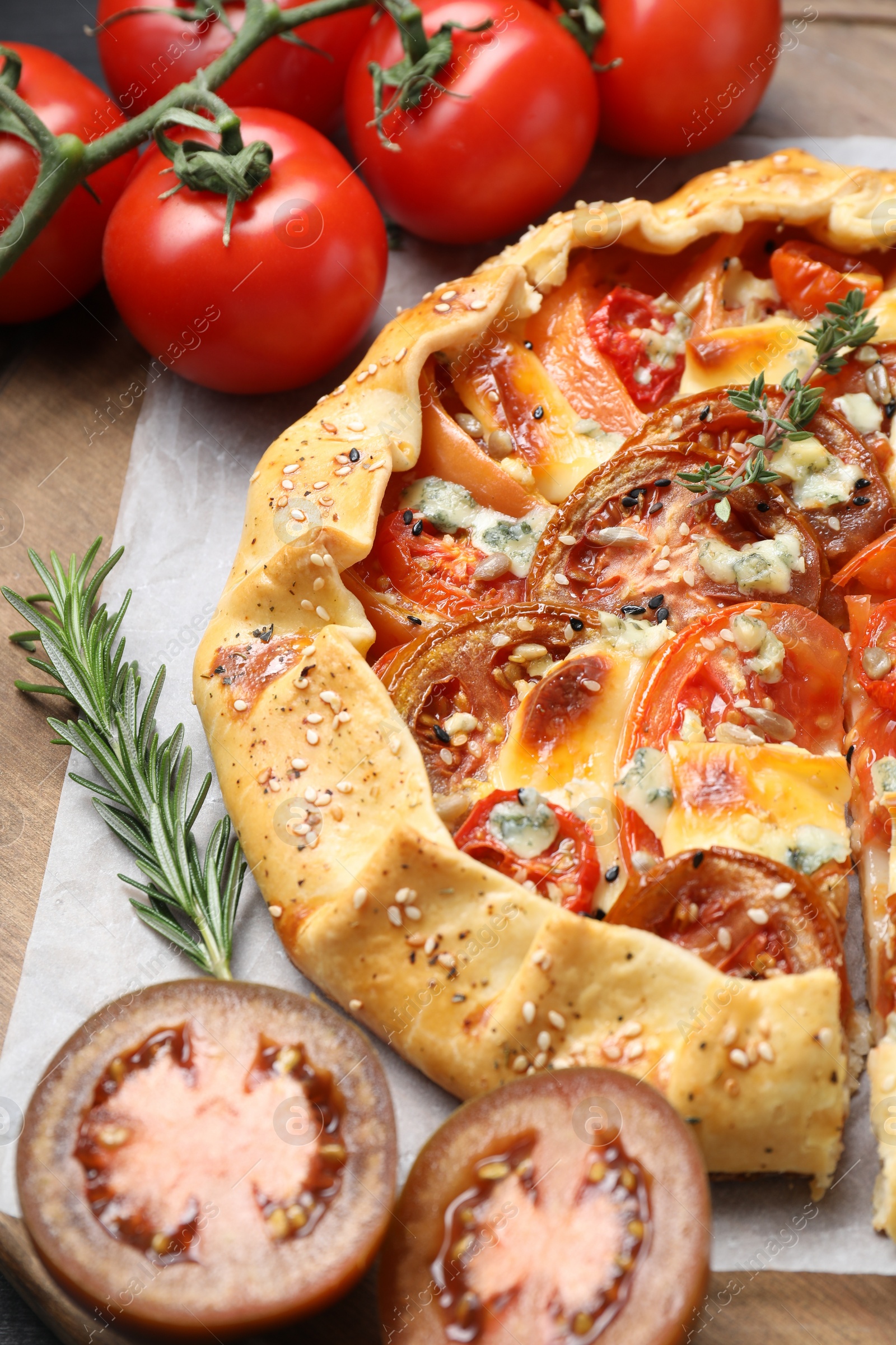 Photo of Tasty galette with tomato and cheese (Caprese galette) on wooden board, closeup