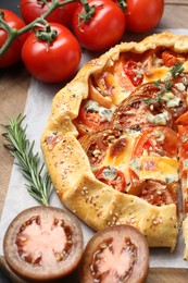 Photo of Tasty galette with tomato and cheese (Caprese galette) on wooden board, closeup