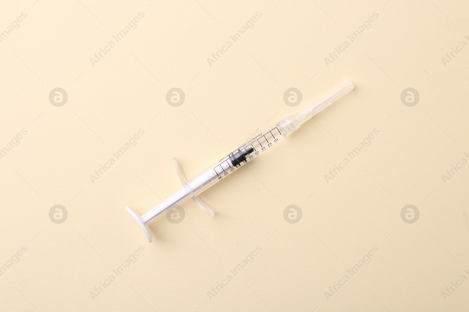 Photo of Injection cosmetology. One medical syringe on beige background, top view