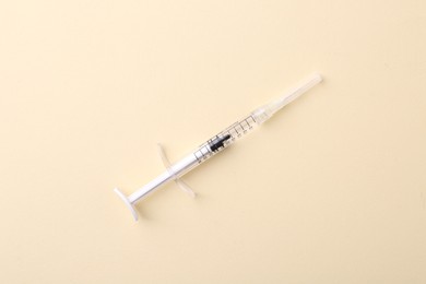 Injection cosmetology. One medical syringe on beige background, top view