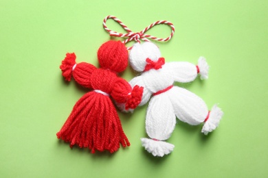 Traditional martisor shaped as man and woman on green background, top view. Beginning of spring celebration