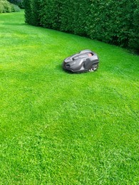 Photo of Modern robot lawn mower on green grass in garden