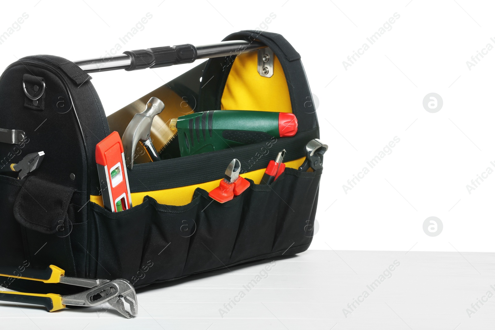 Photo of Bag with different tools on wooden table against white background