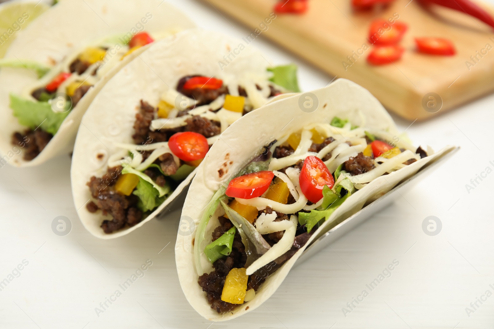 Photo of Delicious tacos with fried meat, vegetables and cheese on white wooden table, closeup