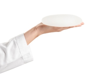 Photo of Doctor holding silicone implant for breast augmentation on white background. Cosmetic surgery