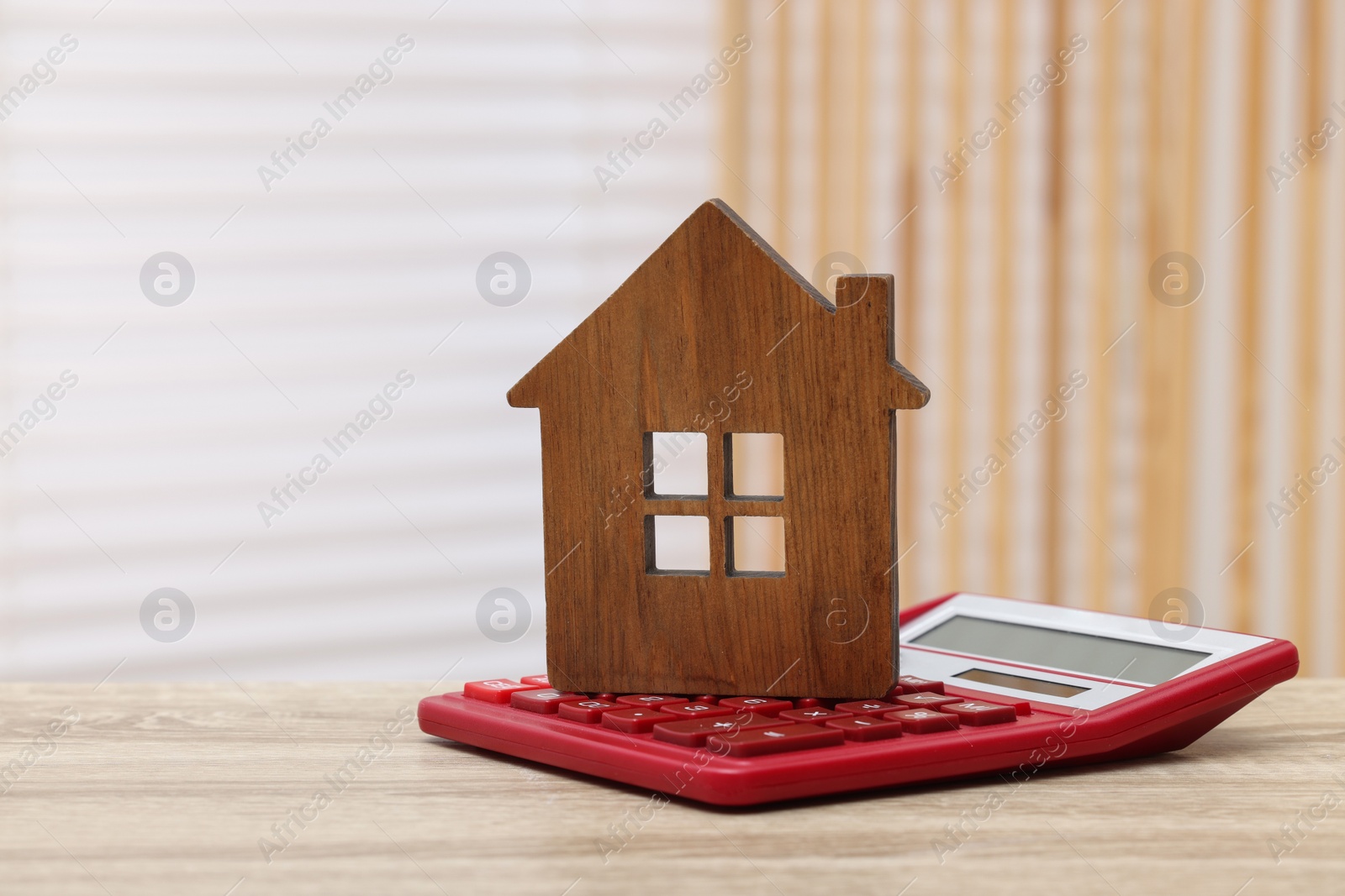 Photo of House model and calculator on wooden table