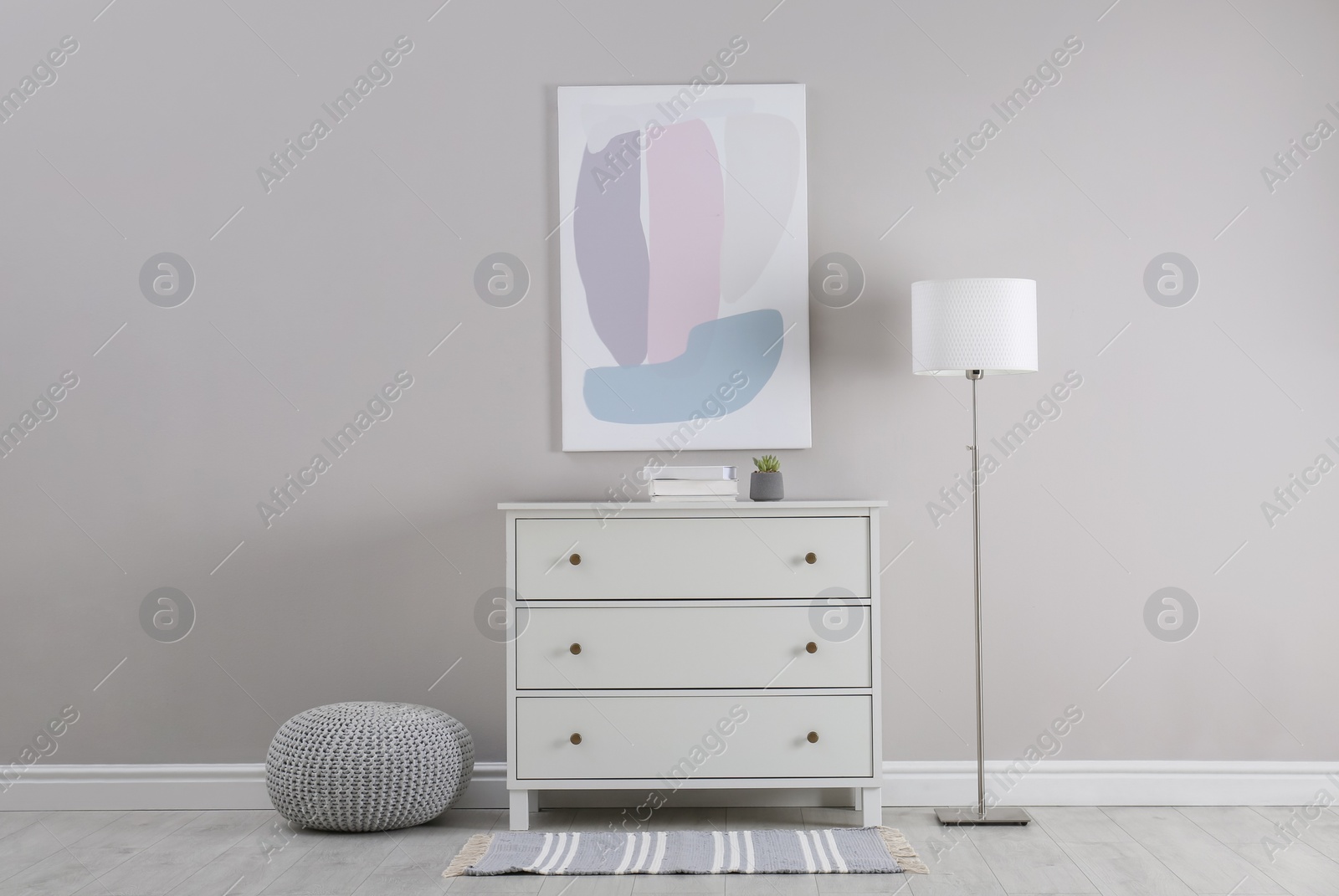 Photo of Stylish room interior with white chest of drawers and floor lamp