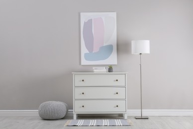 Photo of Stylish room interior with white chest of drawers and floor lamp