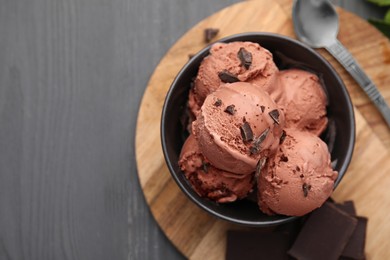 Photo of Bowl with tasty chocolate ice cream on wooden board, flat lay. Space for text