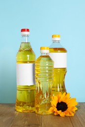 Photo of Bottles of cooking oil and sunflower on wooden table