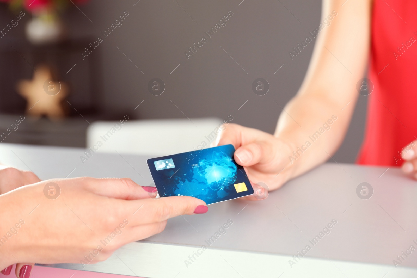 Photo of Woman giving credit card to receptionist at desk in beauty salon, closeup