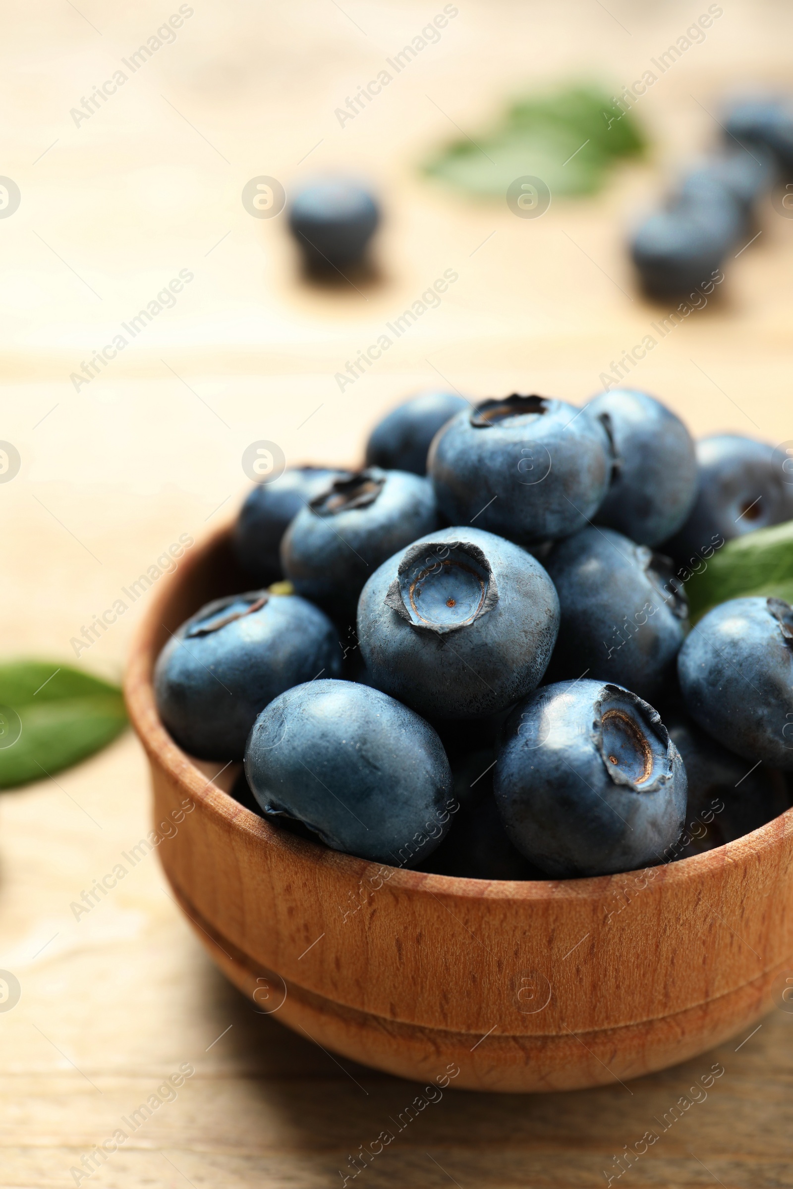 Photo of Bowl of tasty fresh blueberries on wooden table, closeup