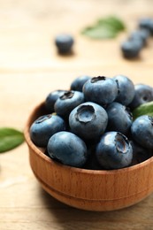 Bowl of tasty fresh blueberries on wooden table, closeup