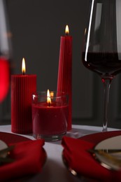 Photo of Place setting with red candles on white table. Romantic dinner